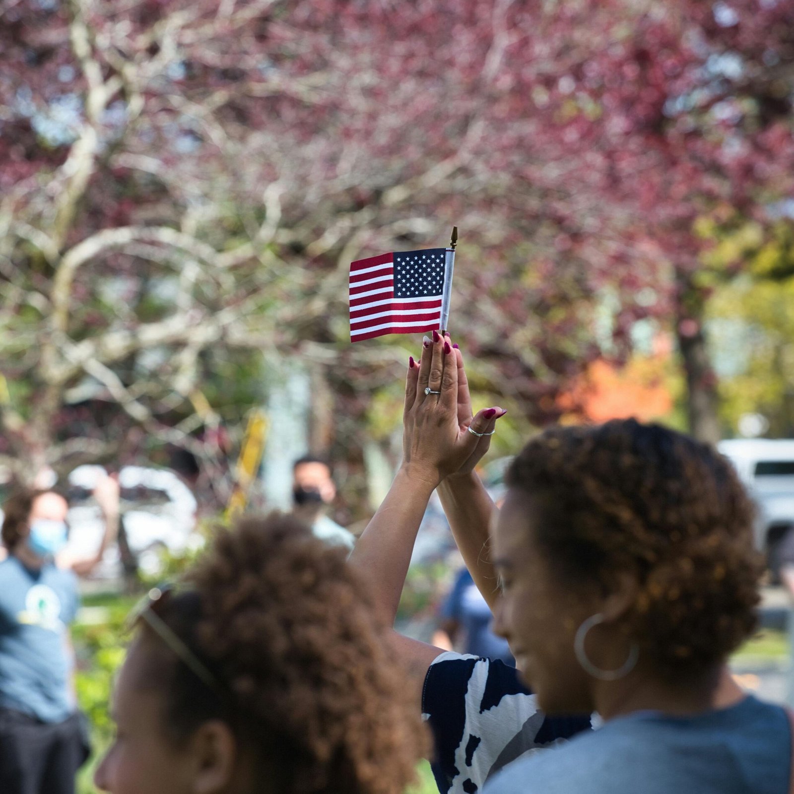 People gathered outdoors waving a small American flag in Bellingham, WA.